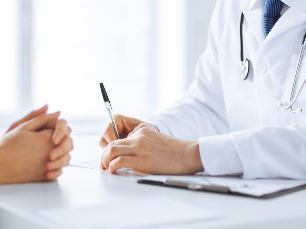 patient and doctor taking notes obisk pri zdravniku specialistu